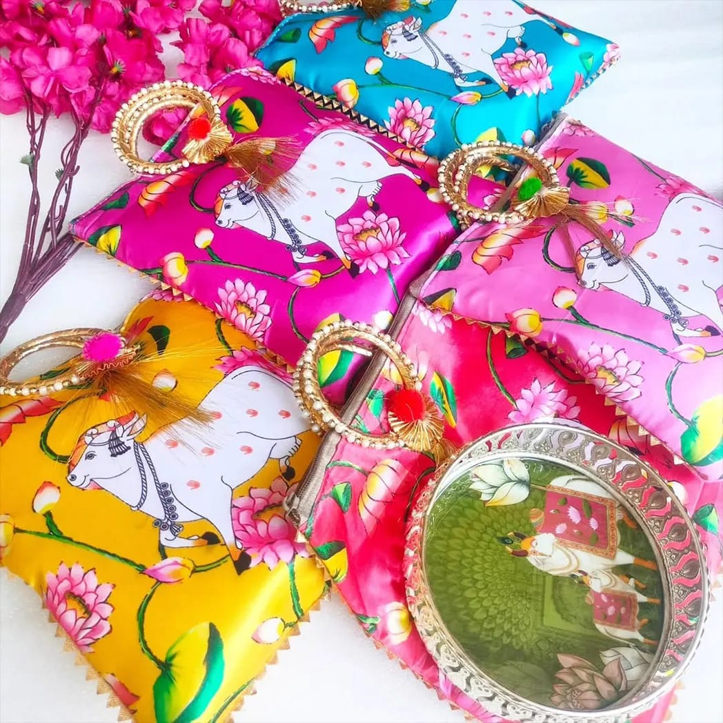 Bright pichwai print zip pouches with gold ring handles and a printed mirror tray