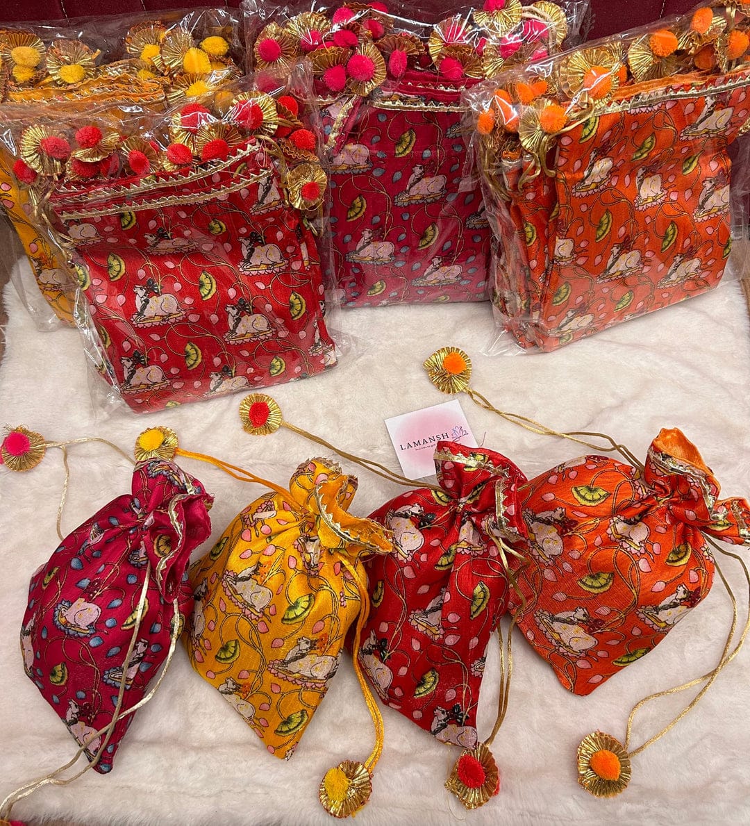 Pichwai cow print potli bags with gold pom-pom drawstrings